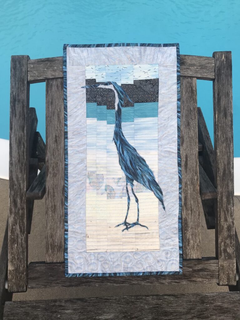 Image of a great blue heron quilt at poolside