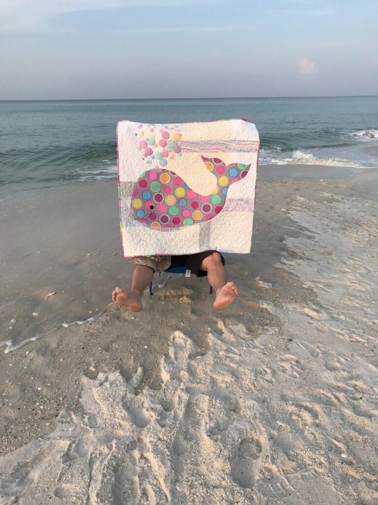 Image of marine saving Bubbles the baby whale quilt at the beach.